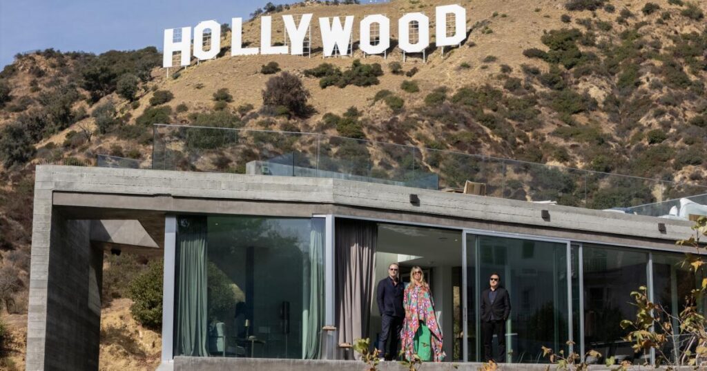 A modern four-story concrete home is built under the Hollywood sign